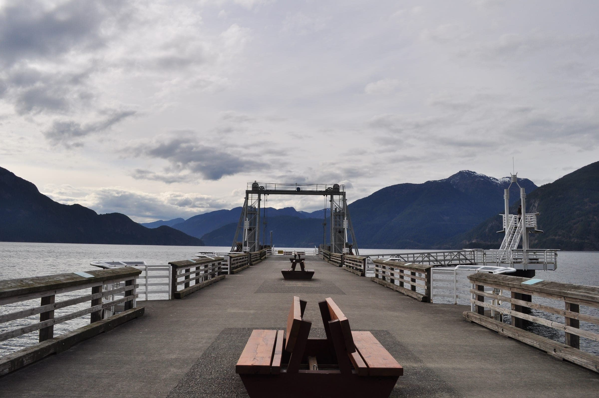 Benches line the old ferry pier at Porteau Cove Provincial Park under a grey sky over Howe Sound.