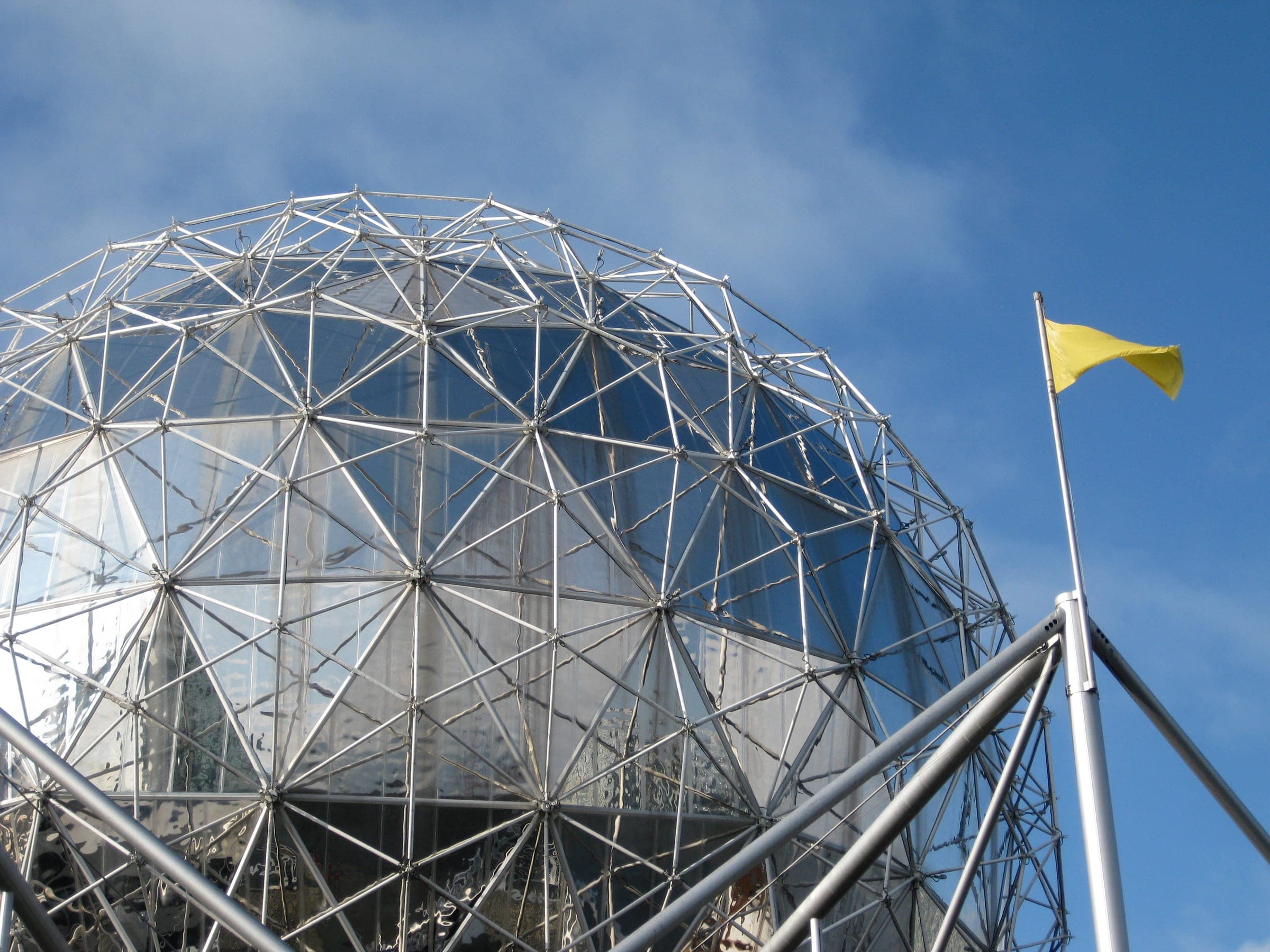 Steel struts and triangular panels make up the geodesic dome of Science World against a blue sky.