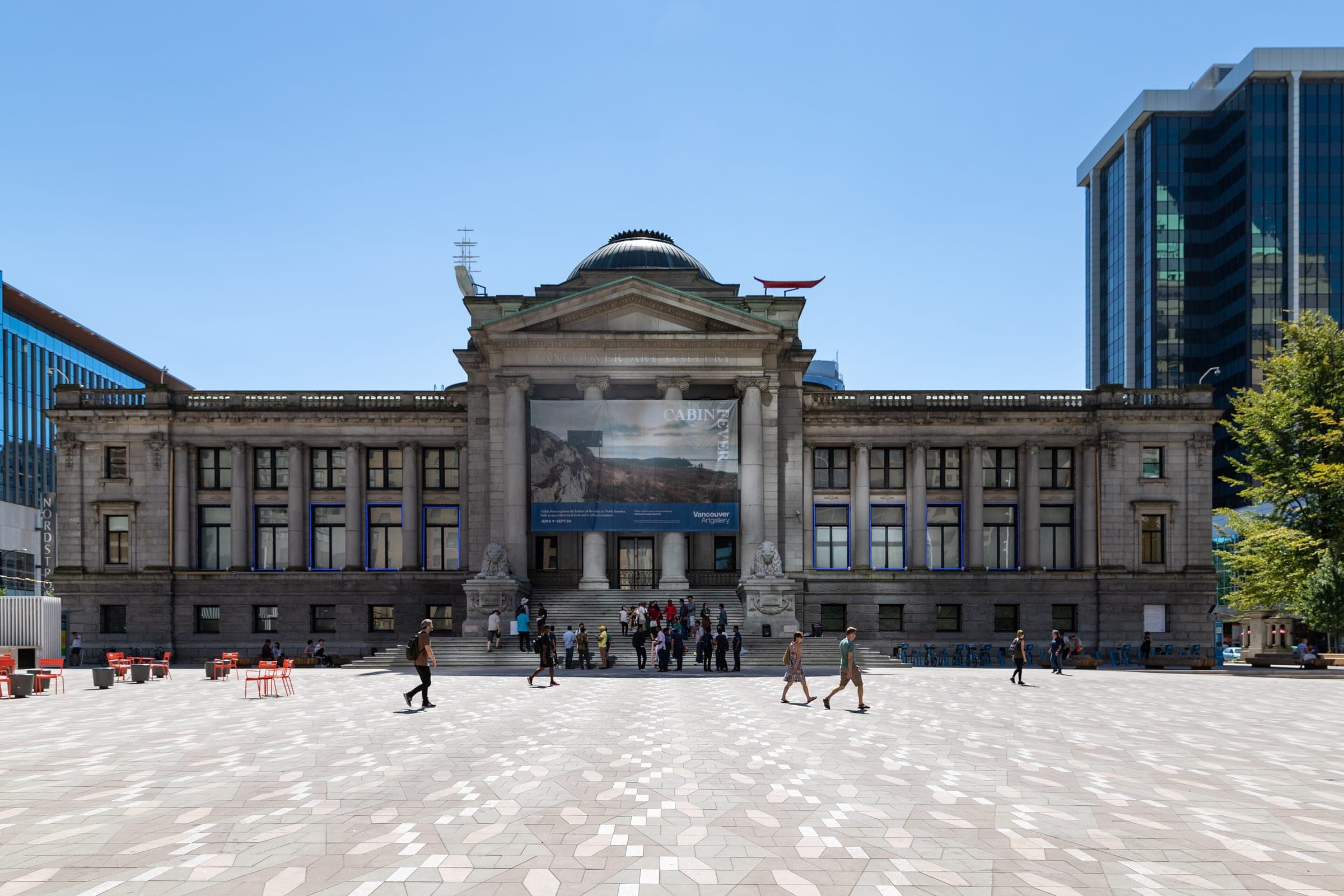 The domed Robson Street front of the Vancouver Art Gallery faces a wide paved plaza on a clear day.