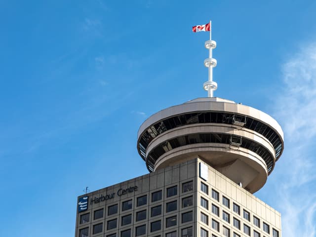 The round observation deck of the Vancouver Lookout crowns Harbour Centre against a blue sky.