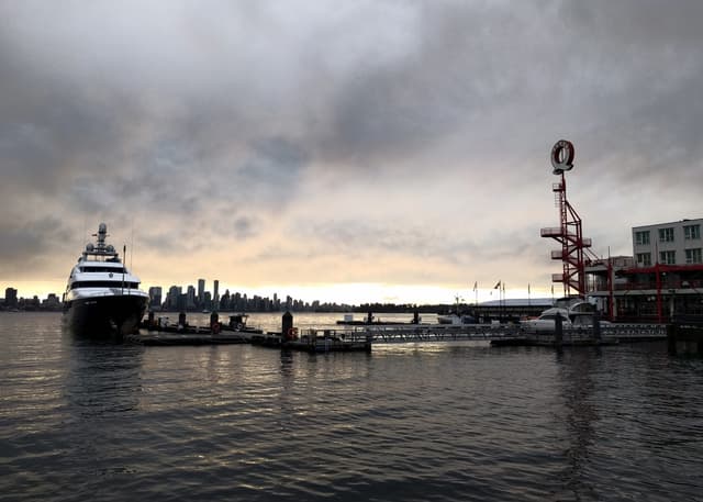 Lonsdale Quay's red Q tower and moored yachts face the downtown Vancouver skyline under November cloud.