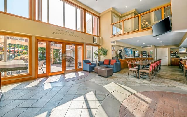 Sunlit lobby and lounge at Econo Lodge Inn & Suites North Vancouver with tall windows and glass doors.
