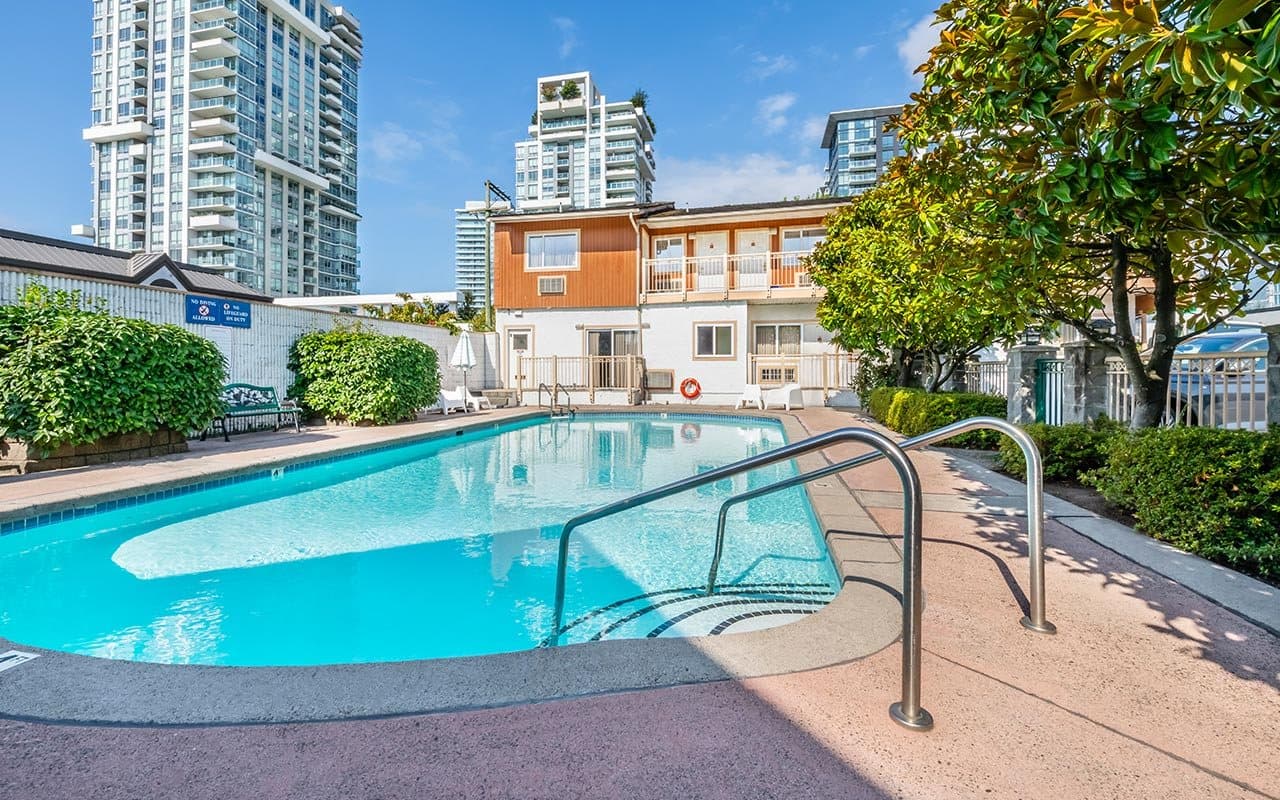 Outdoor pool at Econo Lodge Inn & Suites North Vancouver with the guest rooms behind it.