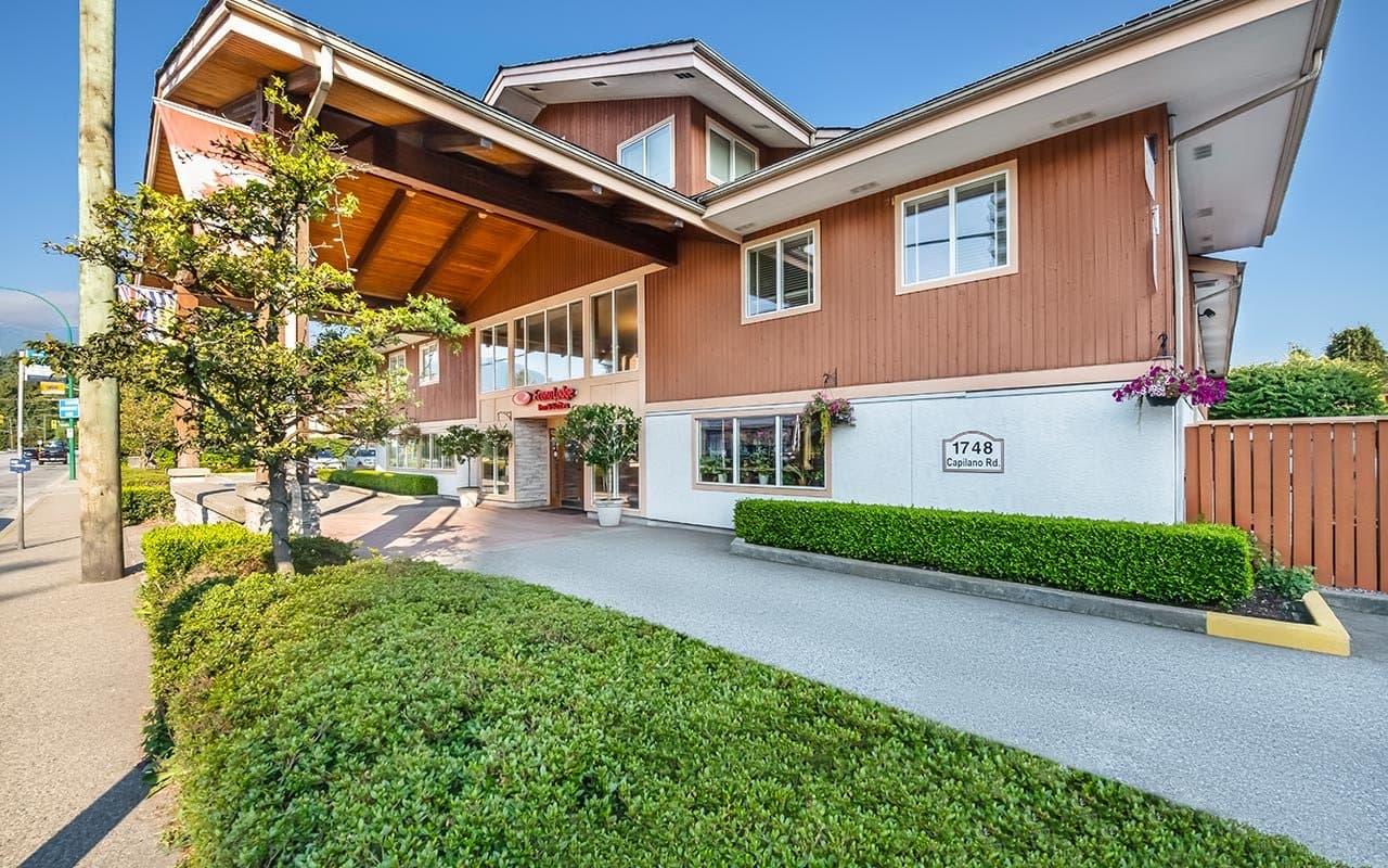 Econo Lodge Inn & Suites North Vancouver with its cedar-clad entrance and landscaped frontage on a sunny day.