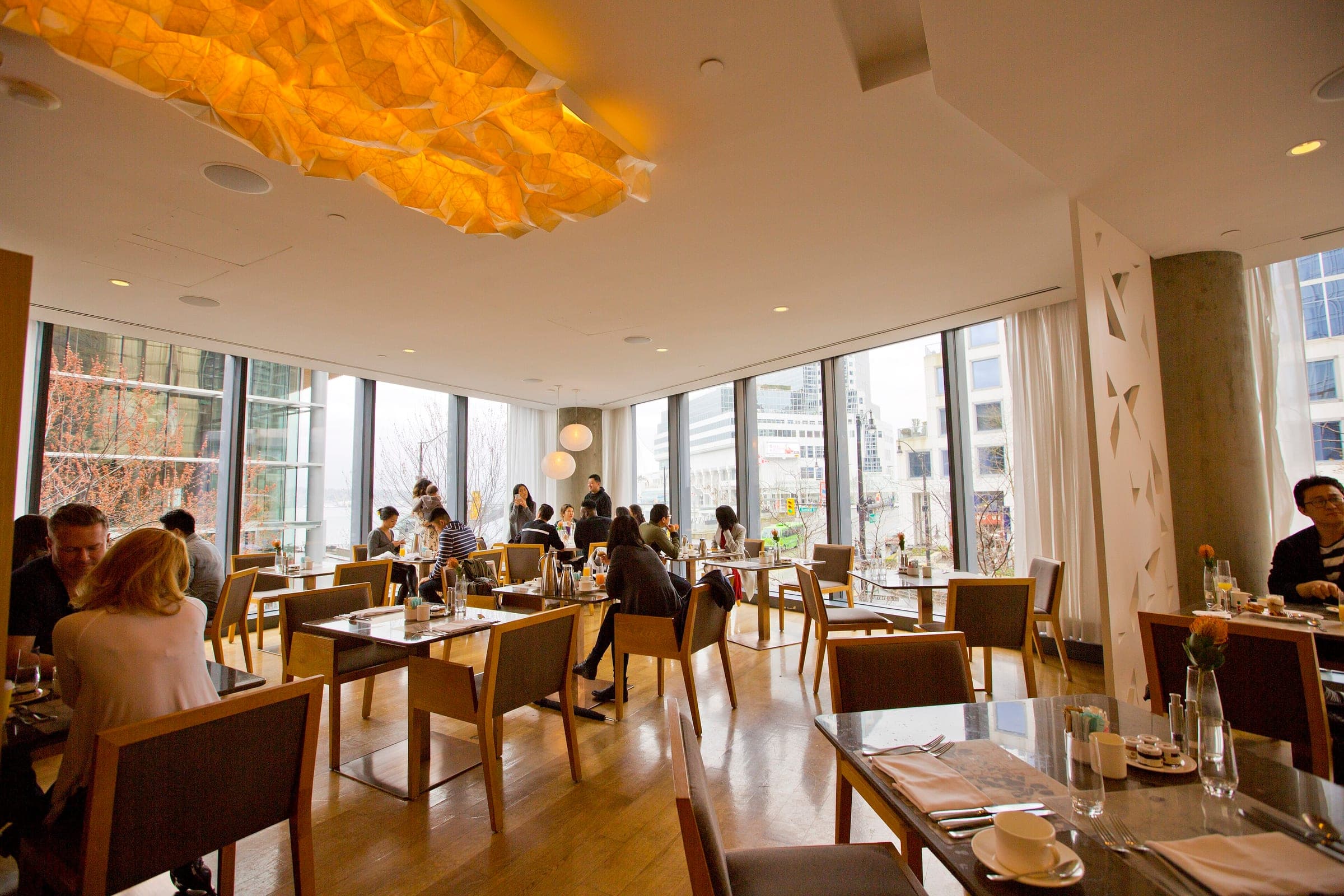 Diners sit under a sculpted paper light in the window-lined dining room of the Fairmont Pacific Rim.