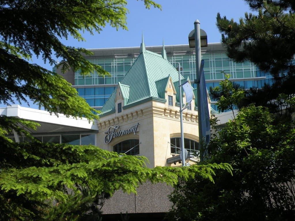 Fairmont Vancouver Airport seen through evergreens from Vancouver Airport Park, with its copper-green roof.