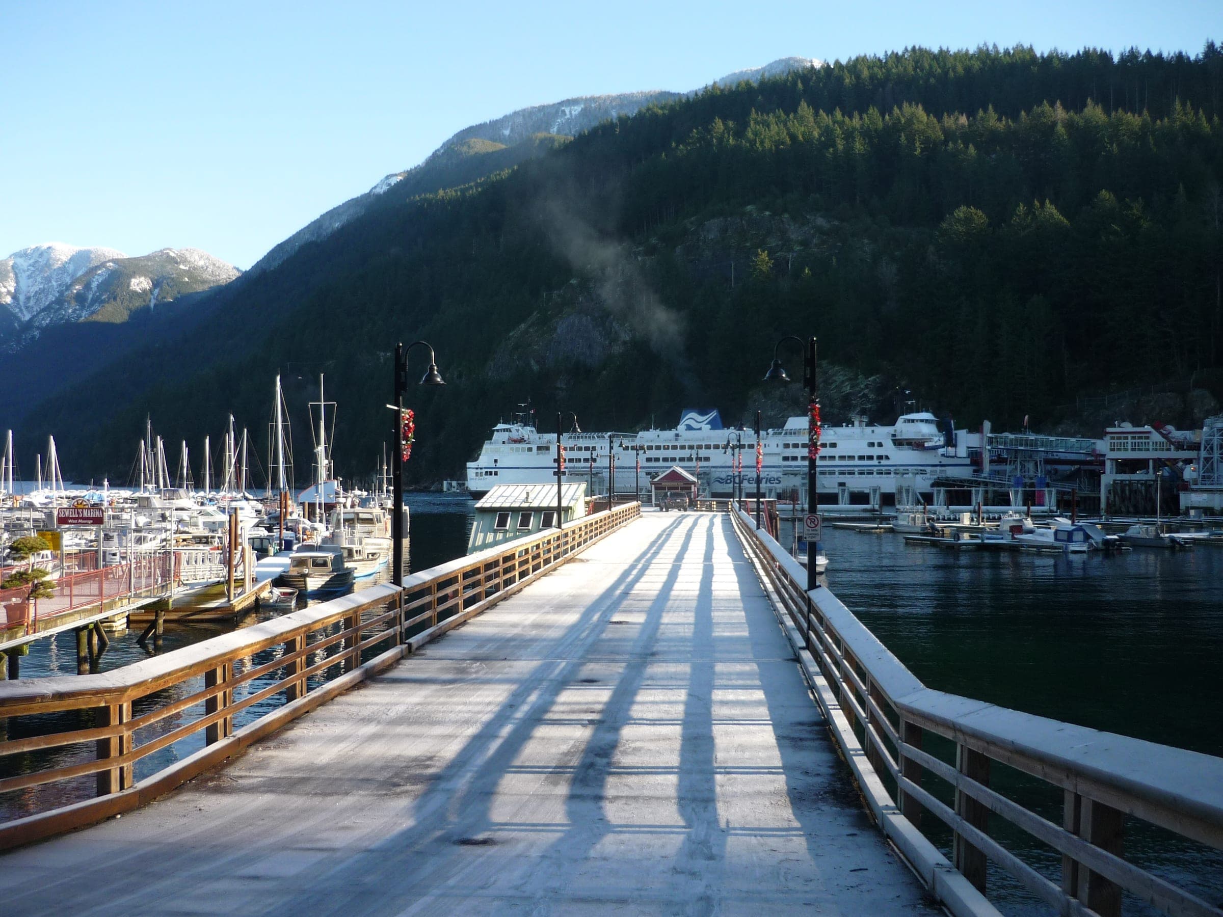 The public pier at Horseshoe Bay runs out past the marina toward snow-capped peaks on a clear December day.