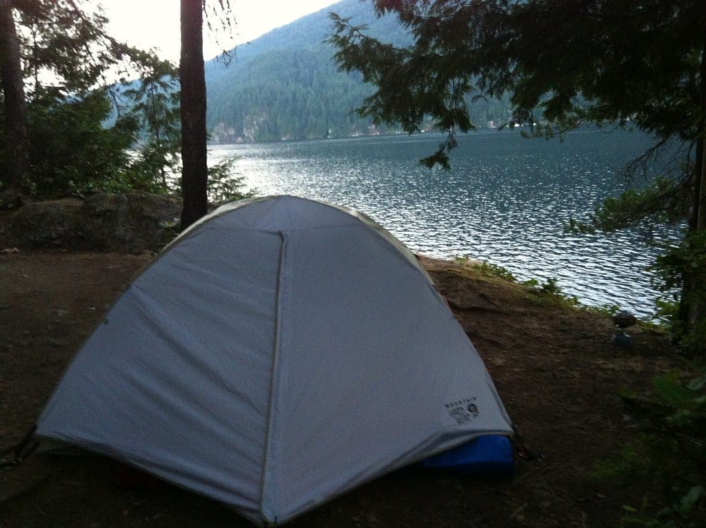 A tent stands on a forest site at the North Twin Island campground above the calm water of Indian Arm.