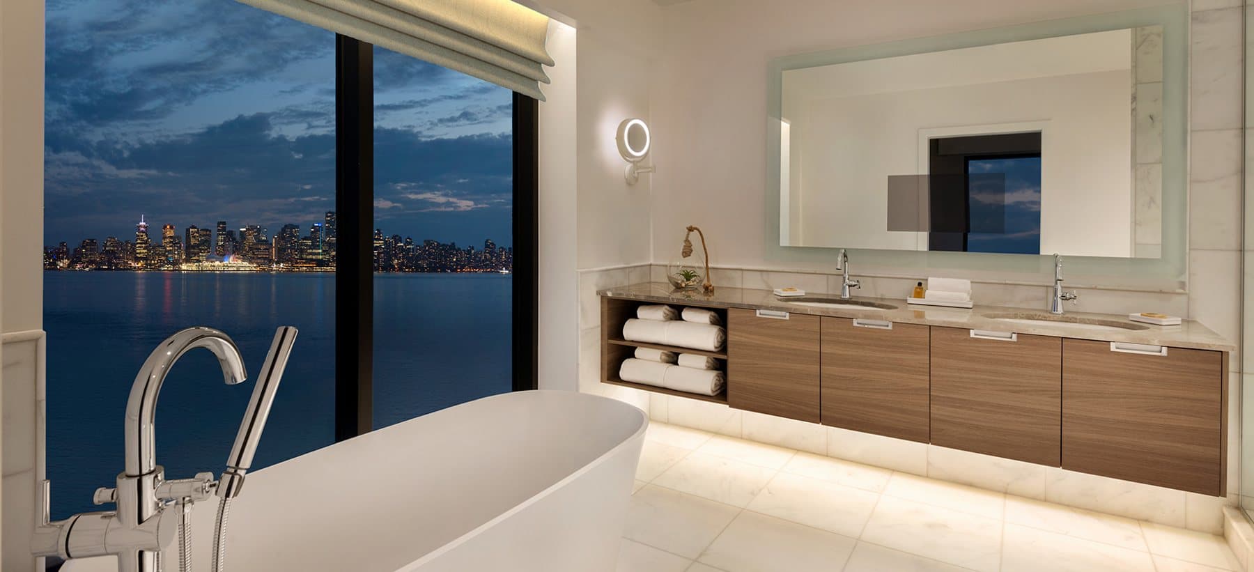 Bathroom at Seaside Hotel with a soaker tub beside a window that looks over the water.