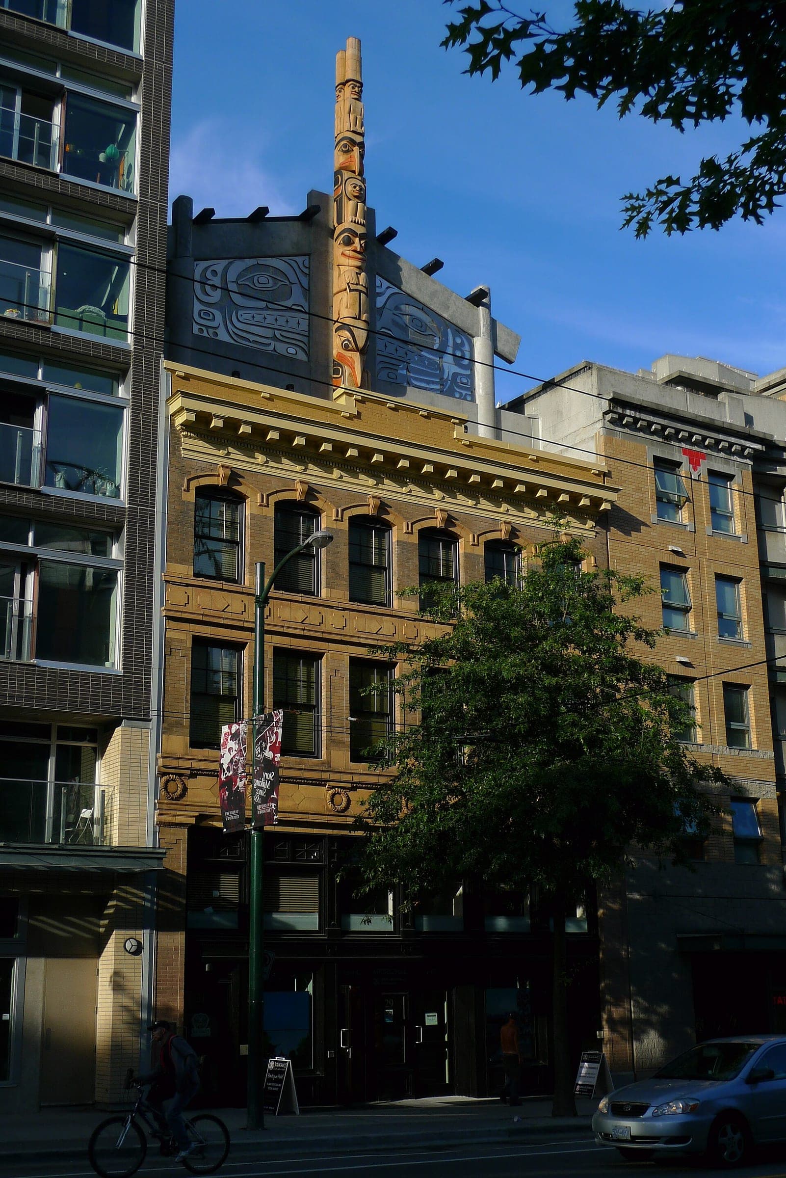 Skwachays Lodge on West Pender Street in late sun with its carved pole above the cornice.