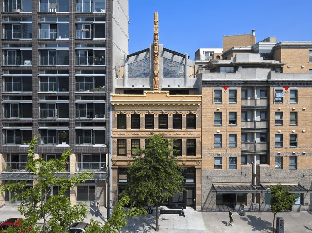 Brick heritage facade of Skwachays Lodge on Vancouver's Water Street with a carved totem on the roofline.