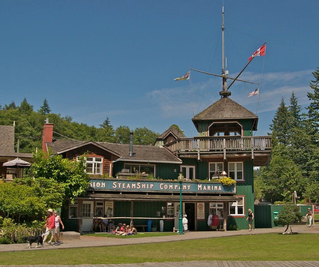 The green Union Steamship Company Marina building faces a lawn on the Snug Cove boardwalk on Bowen Island.