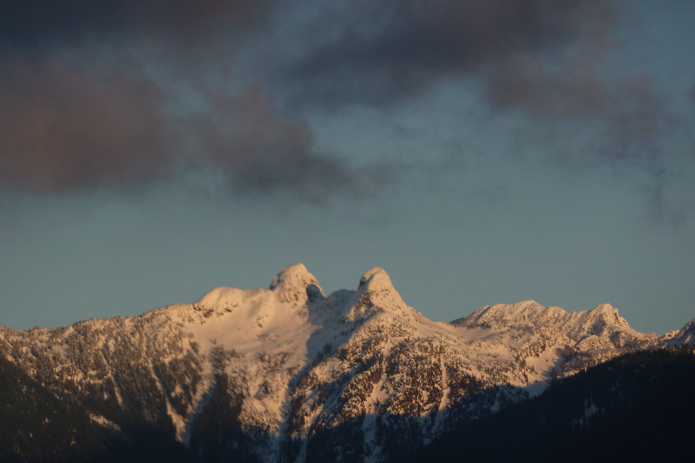 Snow on the Lions glows pink at sunset in a January view north from Central Lonsdale.