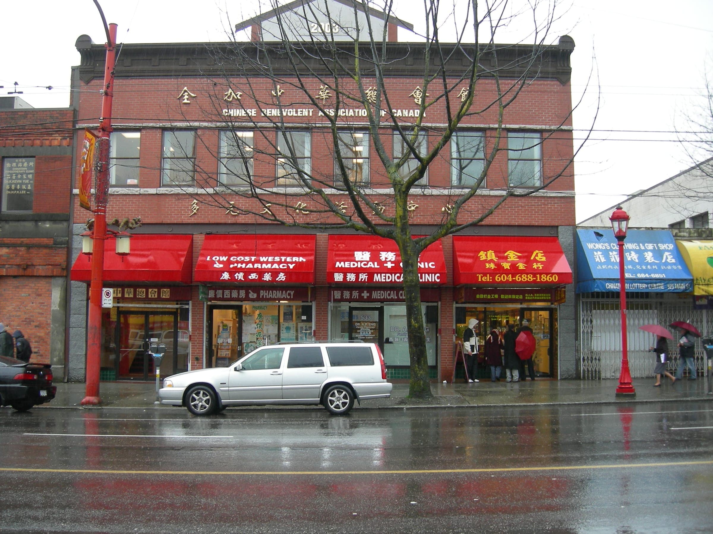 Rain wets the street outside the Chinese Benevolent Association building and its red awnings in Chinatown.