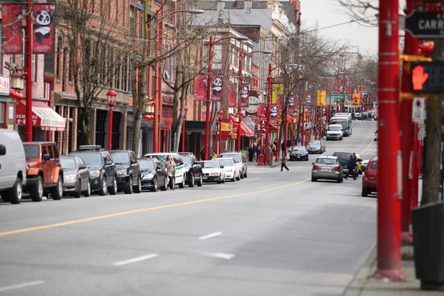 Red lamp poles and painted banners run along East Pender Street through Vancouver's Chinatown.