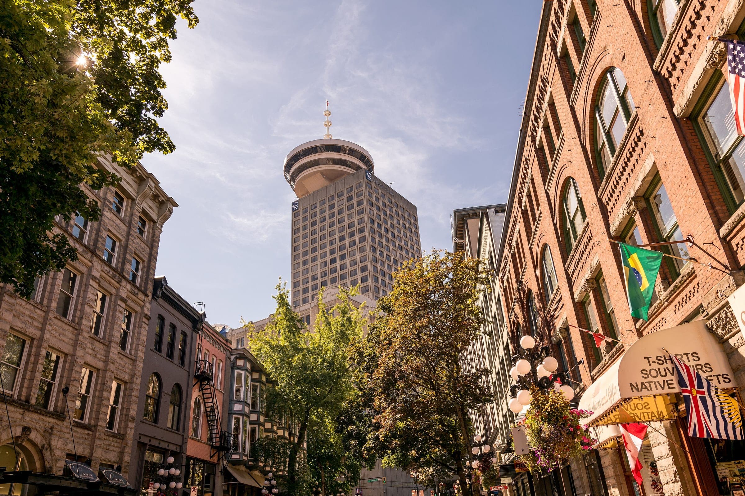 Old brick facades and hanging baskets line a Gastown street below the Harbour Centre tower.