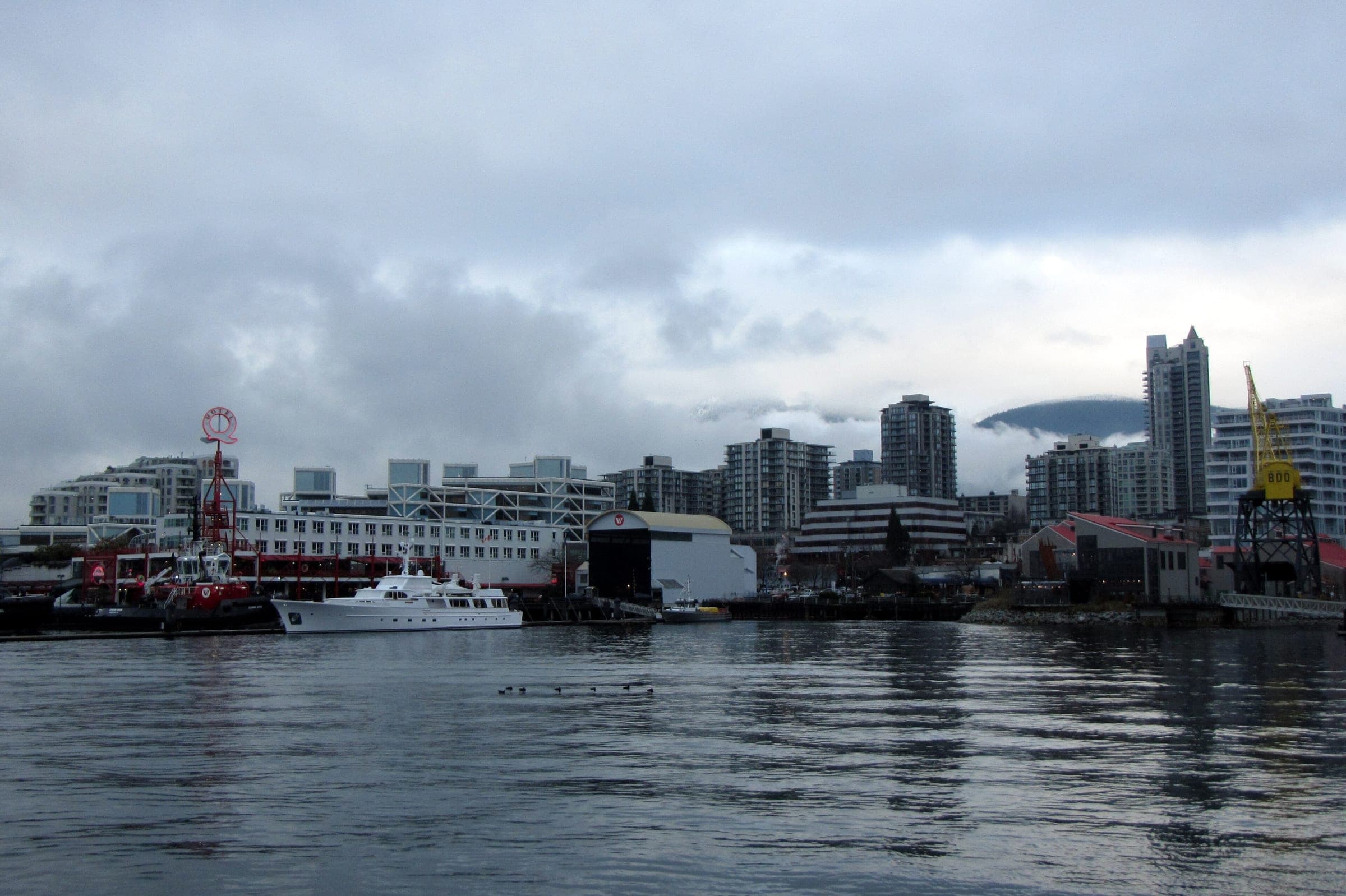 Low cloud hangs over the Lower Lonsdale waterfront, where the Shipyards crane stands beside the harbour.