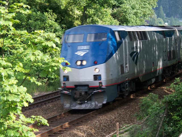 An Amtrak Cascades train rounds a curve through the trees at Mukilteo, Washington, on the Seattle route.