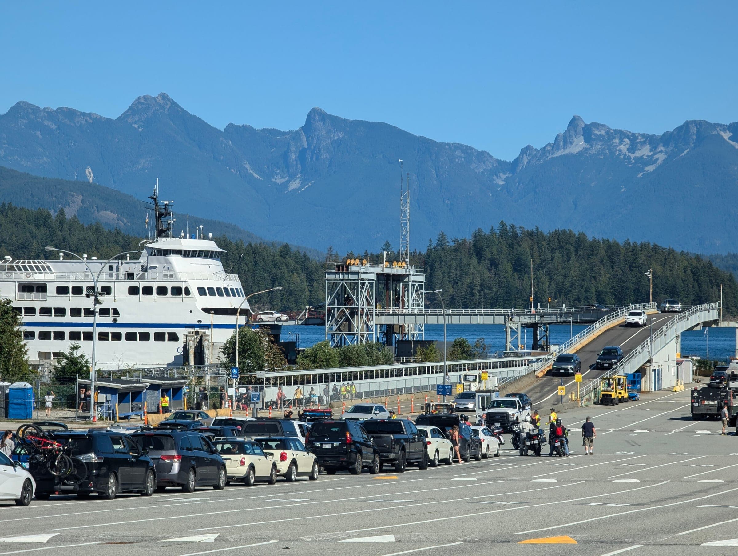 A BC Ferries vessel docks at the Langdale terminal with the Howe Sound mountains behind it.