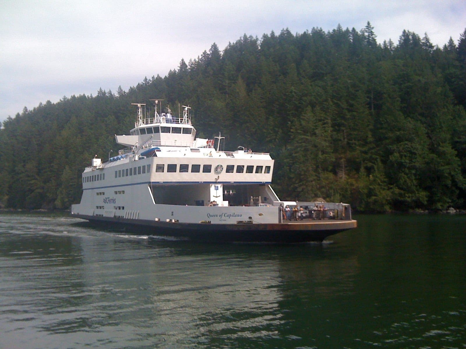 The Queen of Capilano arrives at Bowen Island with forested hills along the shore.