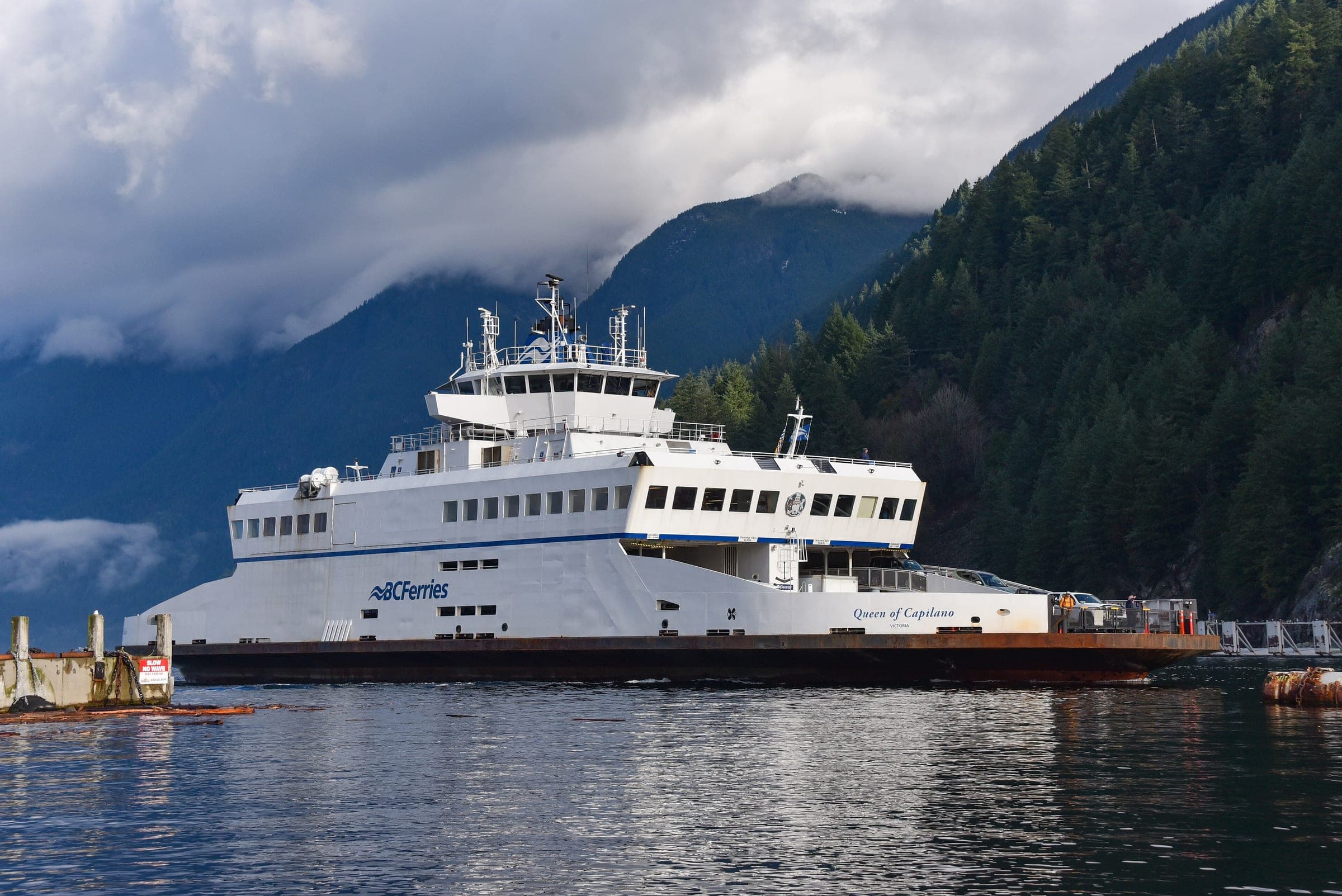 The BC Ferries vessel Queen of Capilano sits at Horseshoe Bay under low cloud and forested slopes.