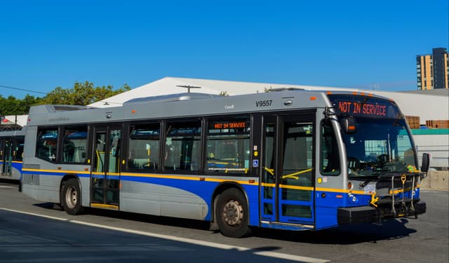 A Coast Mountain Bus Company bus in TransLink colours stands at a stop on a sunny day.
