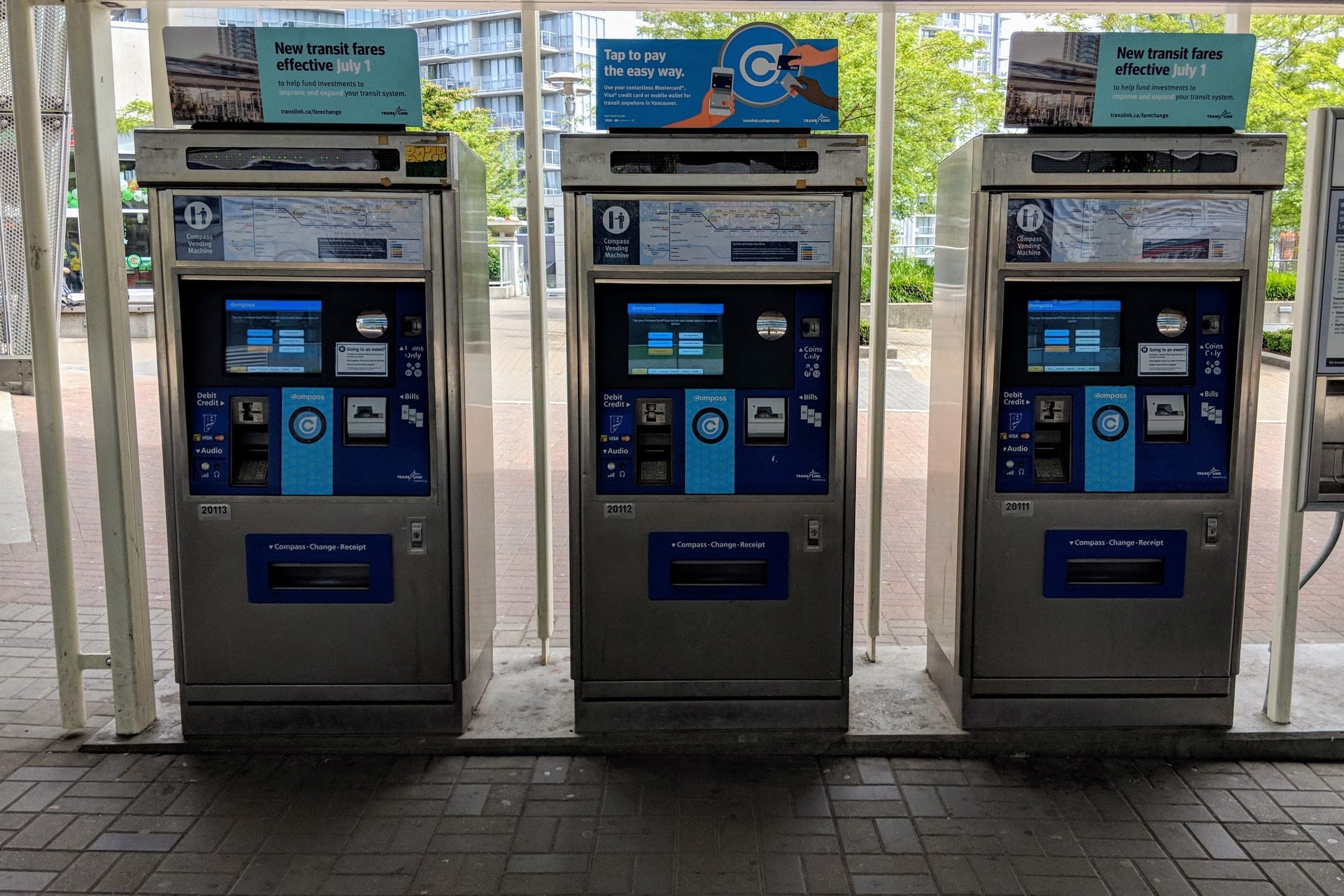 Three Compass vending machines stand in a row at King George SkyTrain station.