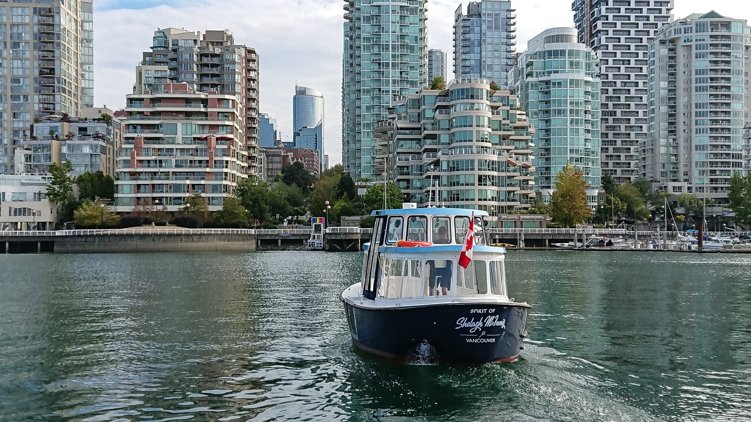 A False Creek Ferries water taxi crosses False Creek in front of the Vancouver waterfront towers.