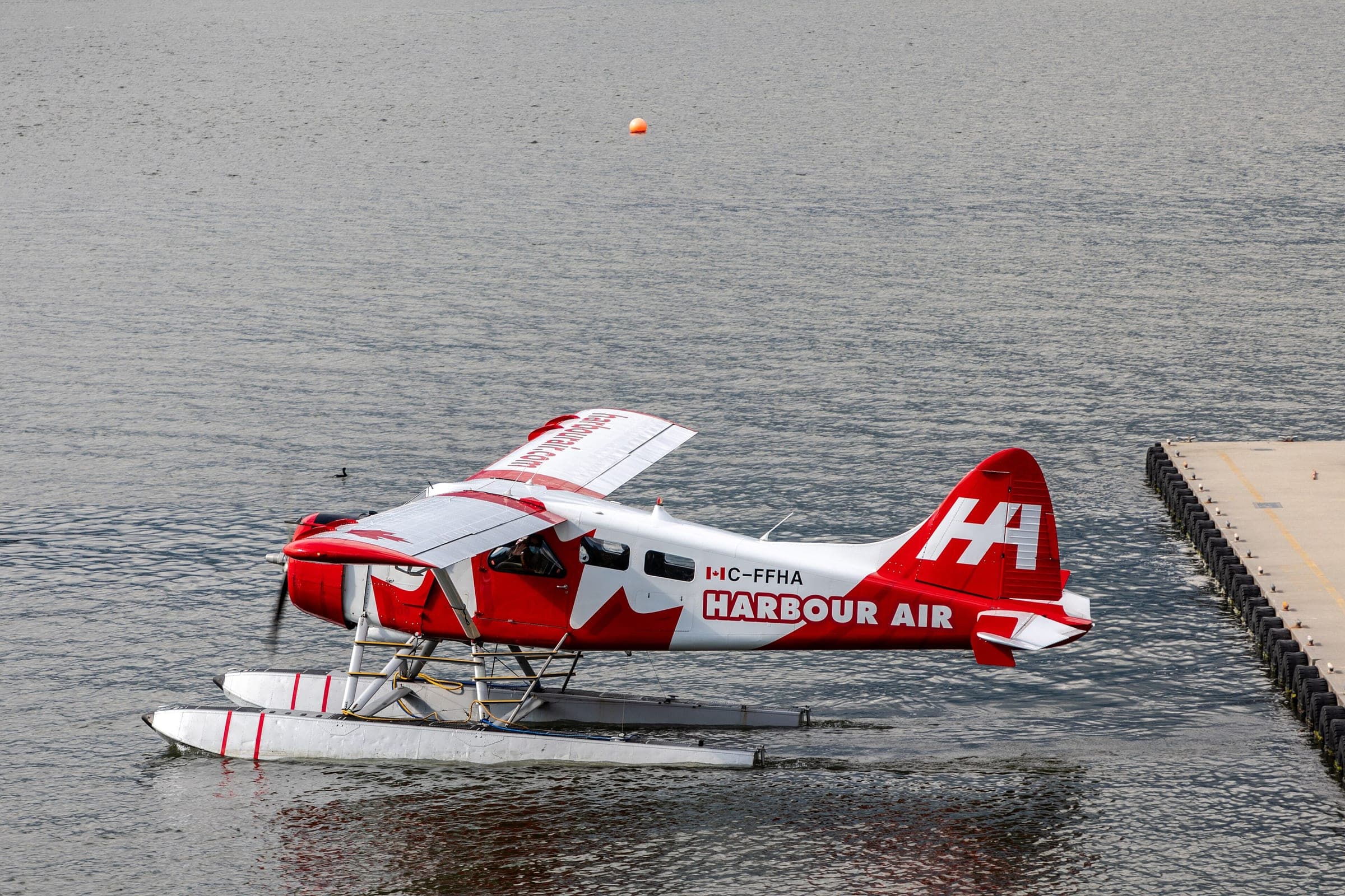 A red and white Harbour Air floatplane sits at the dock in Vancouver Harbour.